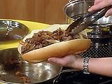 a person is holding a hot dog in their hand while cooking some food on the stove