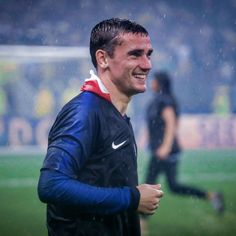 the soccer player smiles as he walks on the field in the rain during a game