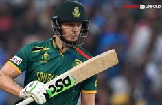 a man holding a cricket bat and wearing a green helmet on top of his head