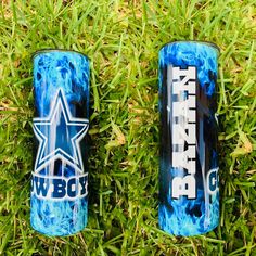 two blue cans sitting in the grass on top of some green grass and one has a white star