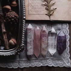 three crystal wands sitting on top of a table next to an old book and mirror