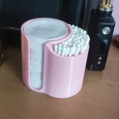 a pink toothbrush holder sitting on top of a wooden table