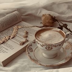 a cup of coffee sitting on top of a saucer next to an open book