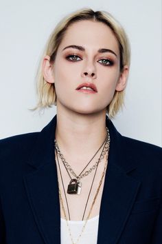 a woman with blonde hair wearing a black blazer and gold chain necklace on her neck