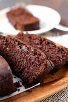 slices of chocolate cake sitting on top of a wooden plate next to another piece of cake