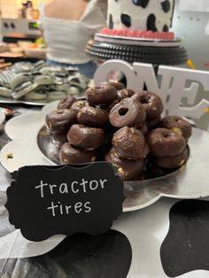 a table topped with chocolate covered donuts and a sign that says tractor tires on it