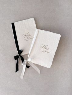 two personalized wedding handkerchiefs tied together with black ribbon and bow on grey background