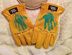 two pairs of yellow gloves with hand prints on them sitting next to a white towel