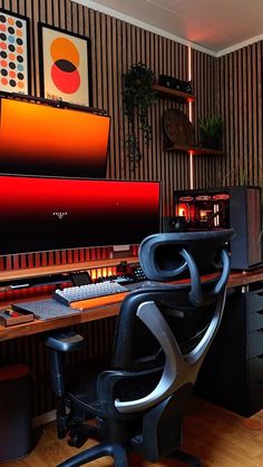 a computer desk with a chair, monitor and speakers on it in front of a striped wall