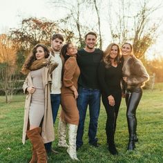 a group of people standing on top of a grass covered field next to each other