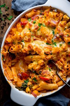 a white casserole dish filled with pasta and chicken, topped with parsley