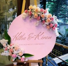 a pink sign with flowers on it that says nilda & kiran engagement ceremony