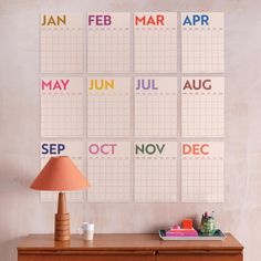 a desk with a lamp and calendars on the wall above it that says, may, june, july, oct, dec