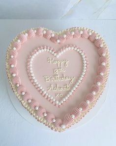 a heart shaped birthday cake with pink frosting