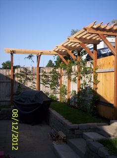 a backyard area with a grill and wooden pergolan