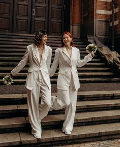 two women in white suits walking down some steps