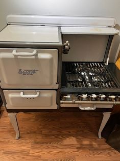 an old fashioned stove with two burners and one oven door open on a wooden floor