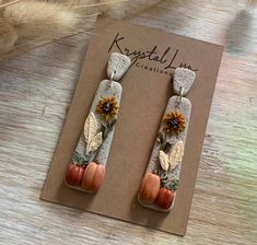 the earrings are made out of stone and decorated with sunflowers, leaves and acorns