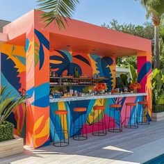 an outdoor bar with colorful painted walls and stools next to a swimming pool, surrounded by palm trees