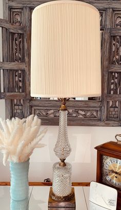 a table with a lamp, vase and clock on it