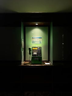 an old fashioned pay phone sitting in a dark room with green walls and flooring