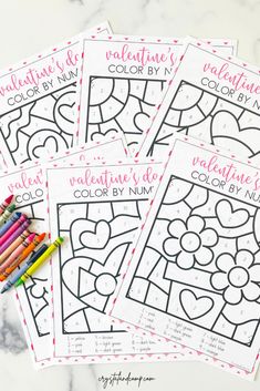 four valentine's day coloring pages with colored crayons on the table next to them