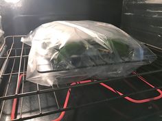 an open oven with some food in plastic bags on the rack and it's door opened