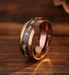 a wedding ring with wood inlays and flowers on the inside, sitting on a wooden table