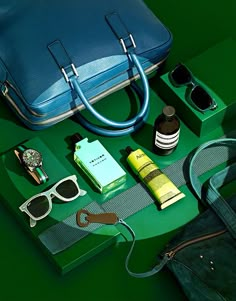 the contents of a blue purse are laid out on a green surface with sunglasses and other items