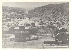 an old black and white photo of a town with mountains in the background as seen from above