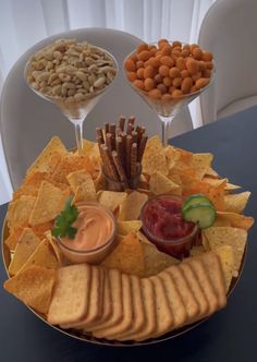 a platter filled with chips, crackers and dips