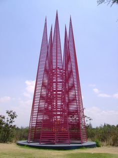 a large red sculpture sitting on top of a lush green field