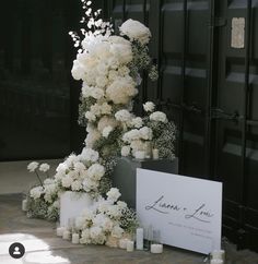 white flowers and candles are on display in front of a black door with a sign