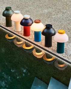 there are many different colored vases on the ledge