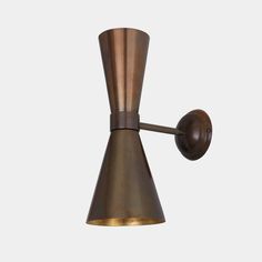 an antique brass wall light with a cone shaped shade on the side and a wooden arm