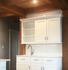 an empty kitchen with white cabinets and marble counter tops in the middle of the room