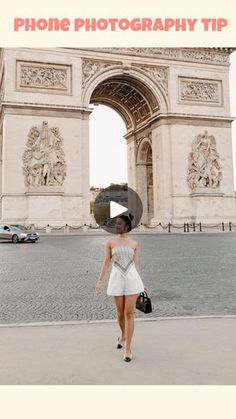 a woman is walking in front of the arc de trioe