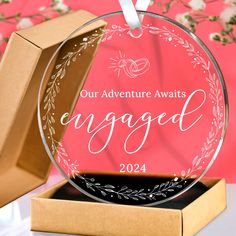 an ornament with the words our adventure awaits engaged on it in front of a pink background