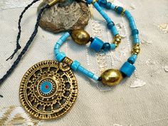 Be unique! Each jewel exists in only one copy and you will be the only one to wear it.  A mid-length necklace, ethnic rustic style: superb pendant of Indian origin! Beautiful and large brass beads that blend perfectly with the blue of the glass beads.  The pendant: 2,4' in diameter in old gold metal and I added a small blue enamel cabochon.  the beads of the necklace:  - large oval brass beads (25 mm)  - large commercial beads in blue opaque glass (15 mm)  - textured blue opaque glass beads (10 Festival Bronze Beaded Necklaces, Bohemian Bronze Beaded Festival Necklace, Bohemian Bronze Beaded Necklace For Festivals, Bohemian Brass Necklace For Festivals, Bohemian Brass Necklaces For Festival, Bohemian Metal Beaded Necklaces With Large Beads, Bohemian Brass Jewelry With Round Beads, Bohemian Gold Beads For Festival, Bohemian Beaded Medallion Necklace