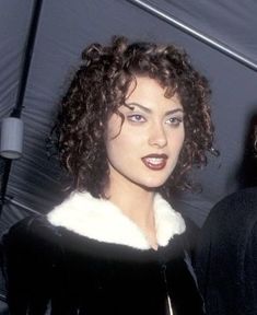 a woman with curly hair standing next to a man