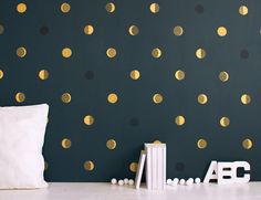 a bed room with a neatly made bed and a wall covered in gold polka dots