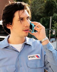 a man talking on a cell phone while wearing a blue shirt