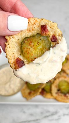 a person holding up a cracker with some type of appetizer on it