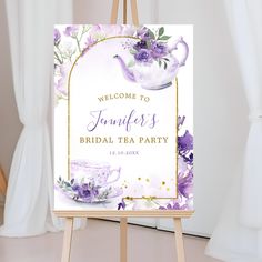 a welcome sign for a bridal tea party with purple flowers and gold trimmings