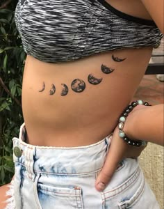 a woman's stomach with phases of the moon tattoo on her lower back and side