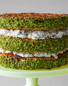 there is a green cake with white and brown toppings on the top of it