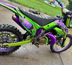 a green and purple dirt bike parked on the street