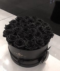 a large round black box with roses on the top and bottom, sitting on a marble floor