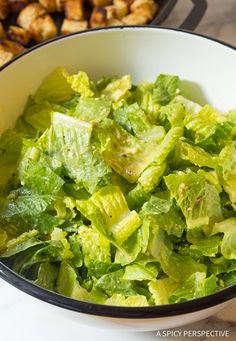 a white bowl filled with lettuce next to chicken