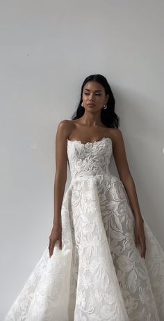 a woman in a white wedding dress leaning against a wall